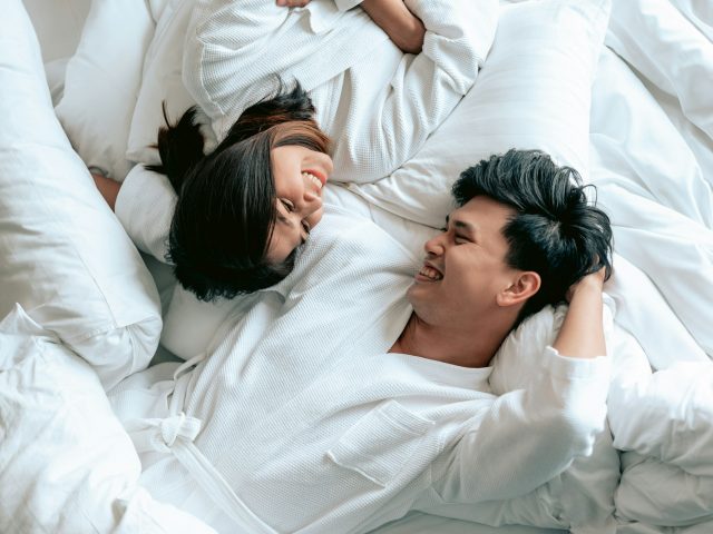 Asian couples is laying on bed in the bed room at modern home.Couple in Valentine day.Love couple