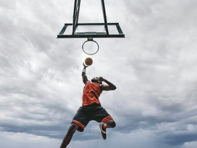 Street basketball player making a powerful slam dunk on the court