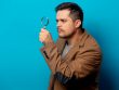 Surprised man with magnifying glass on blue background