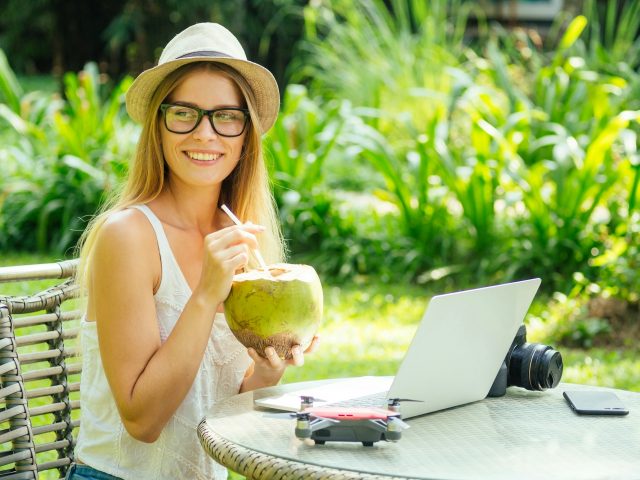 Young photographer woman feeling happy becouse she get money online while sitting at tropical cafe