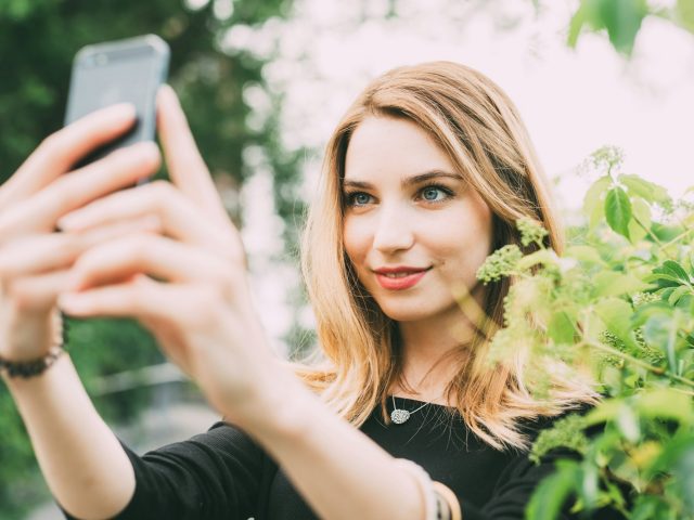 Young woman using smartphone taking selfie